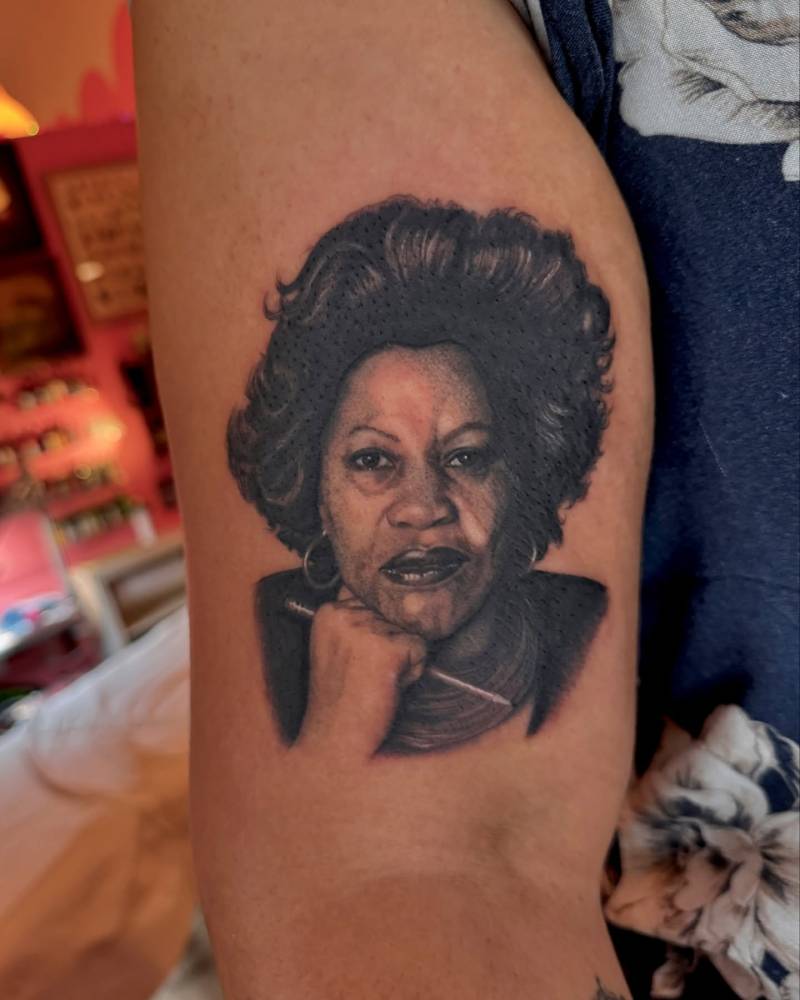 Toni Morrison portrait tattoo in black and grey style done on the upper arm.