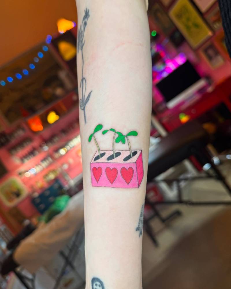 Little growing sprouts tattoo located on the forearm, illustrative style.