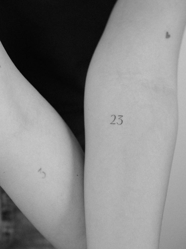 Lettering tattoo of the number 23 located on the inner forearm.