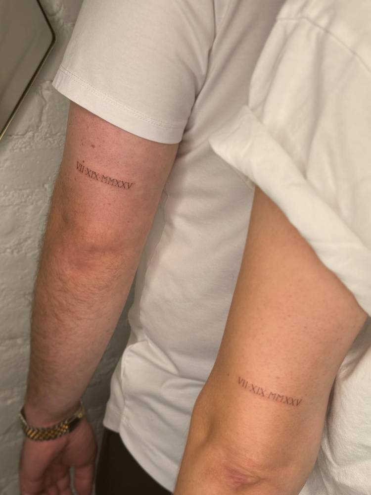Matching date in roman numerals tattoo for couple.