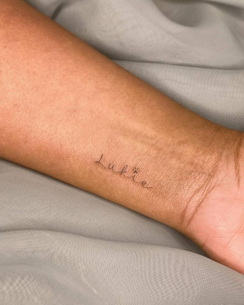 Pet's name tattooed on the wrist in handwritten font.