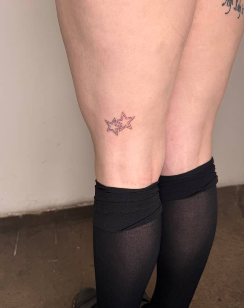 Star couple tattoo in fine line style located on the thigh.