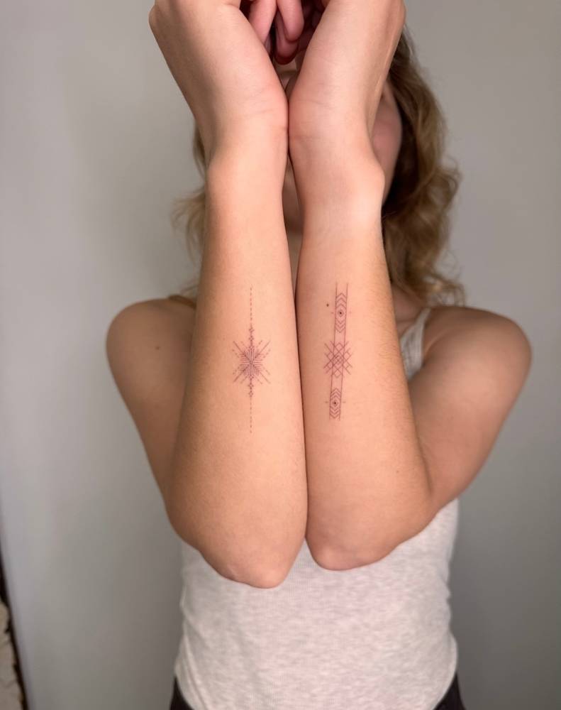 Ornamental designs tattooed on the forearms, fine line style.