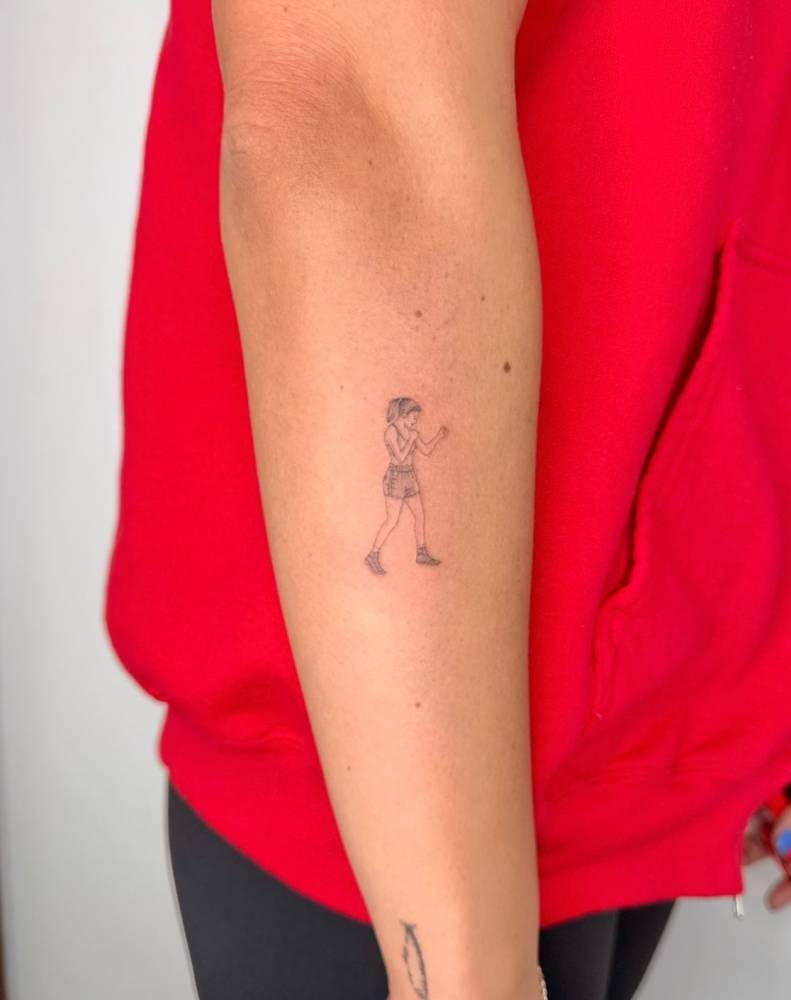 Boxing girl tattoo in fine line style placed on the forearm.