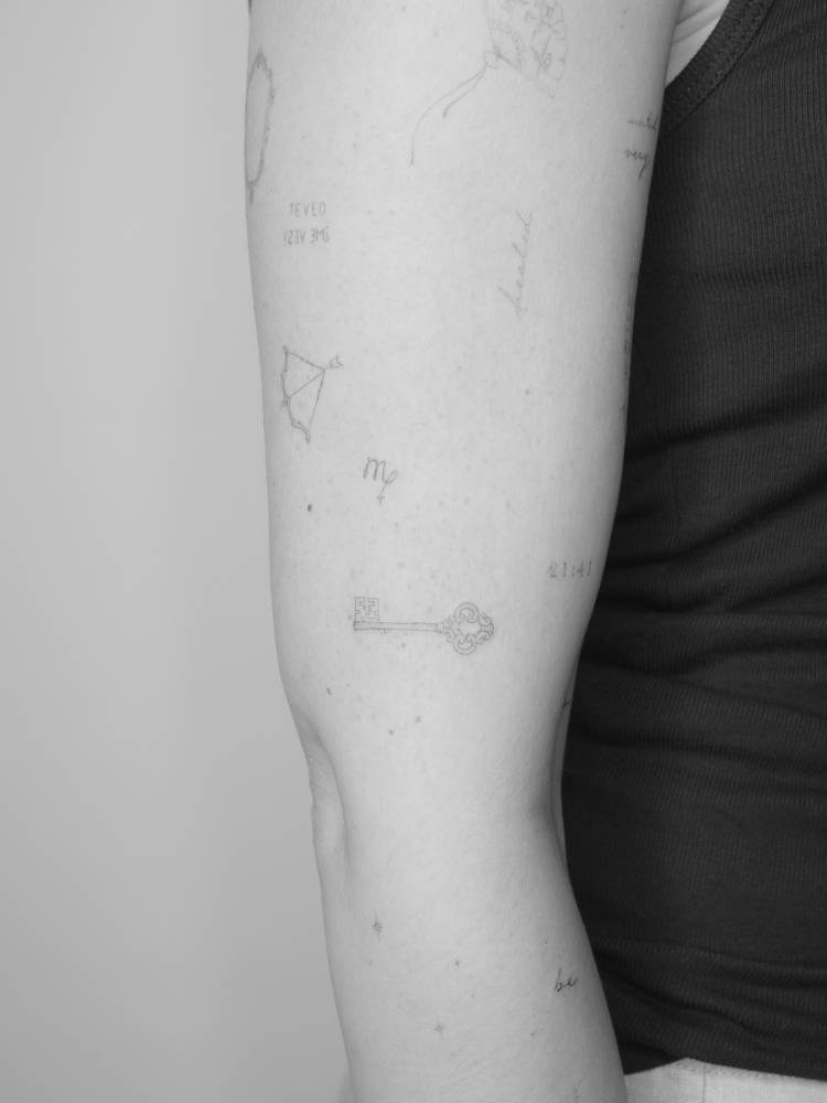 Virgo zodiac symbol and key tattooed on the upper arm.