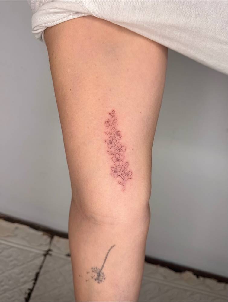 Single needle larkspur tattoo located on the inner arm.