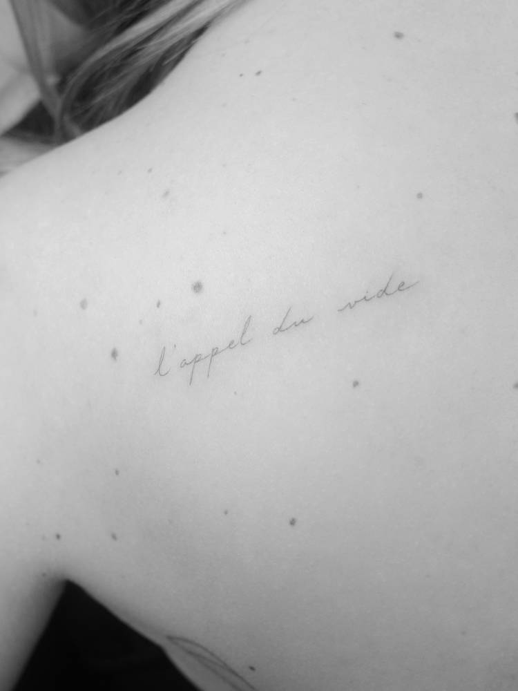 "L'appel du vide" lettering tattoo located on the shoulder blade.