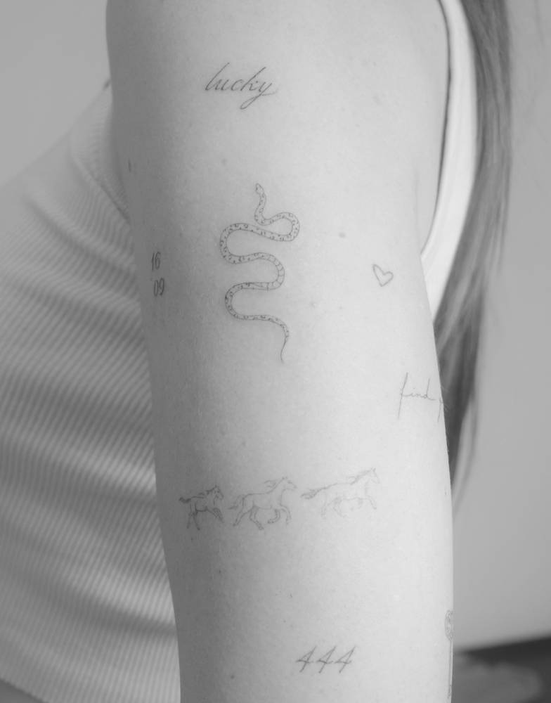 Snake tattoo in fine line style placed on the upper arm.
