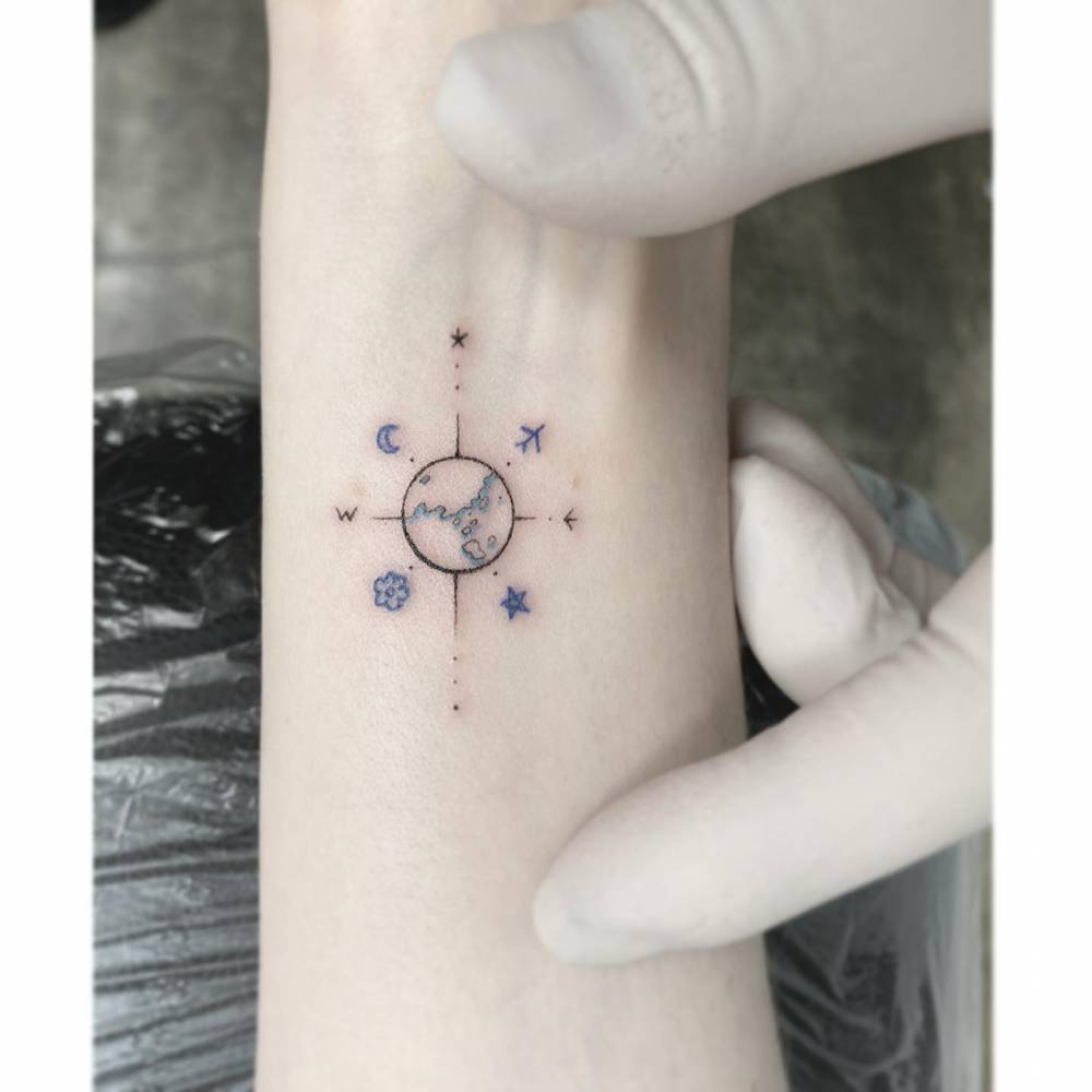 Compass rose tattoo in illustrative style placed on the wrist.