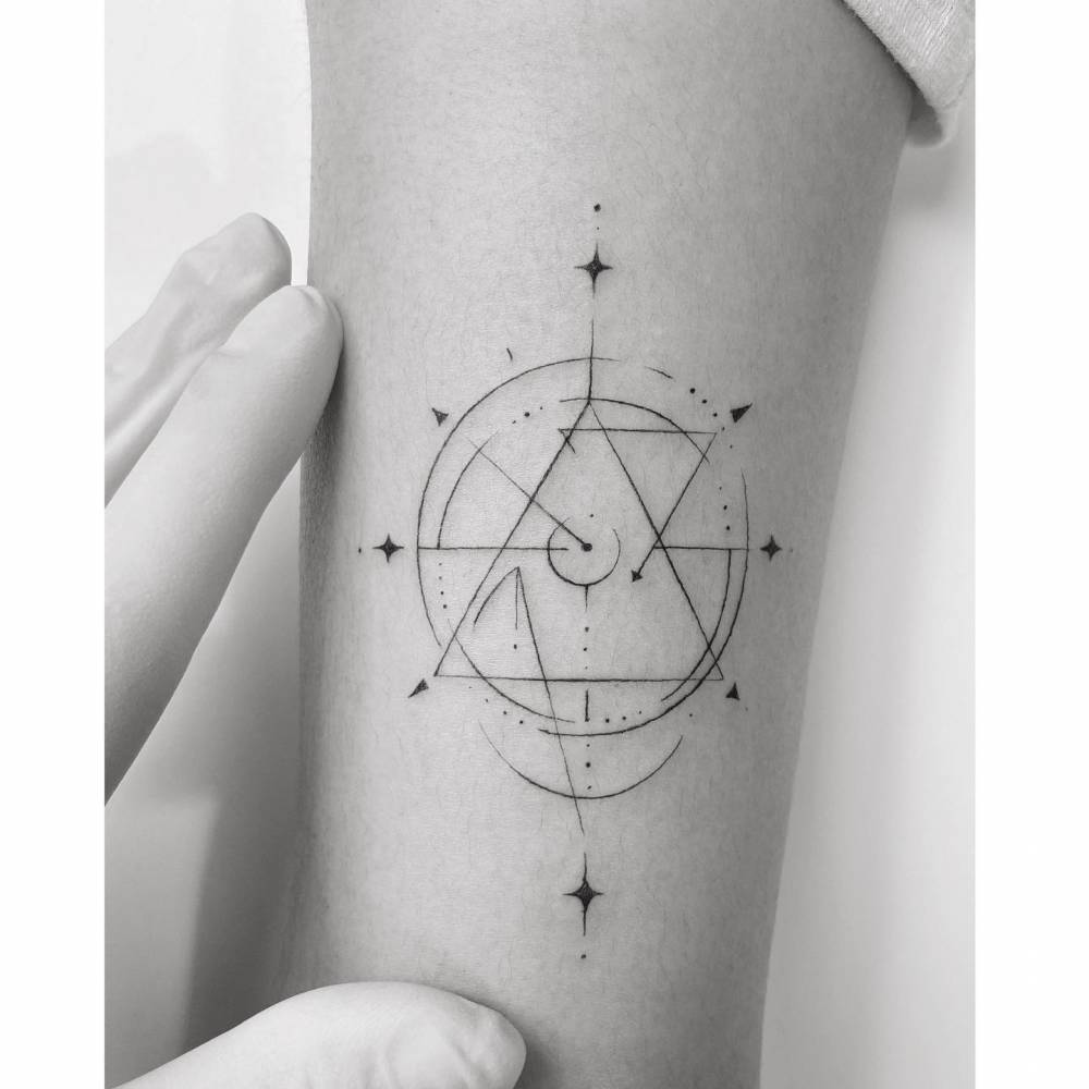 Geometrical compass rose tattoo located on the tricep.