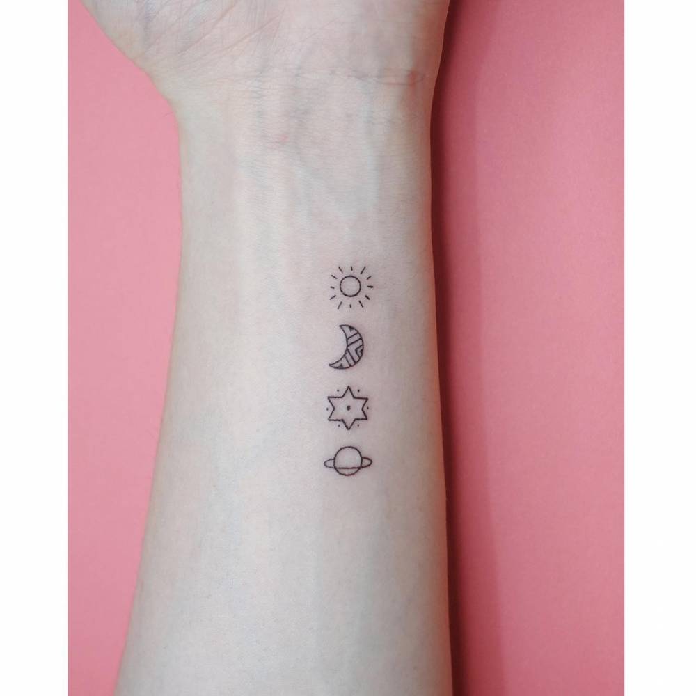Sun, moon, star and Saturn tattoo located on the wrist, minimalistic style.
