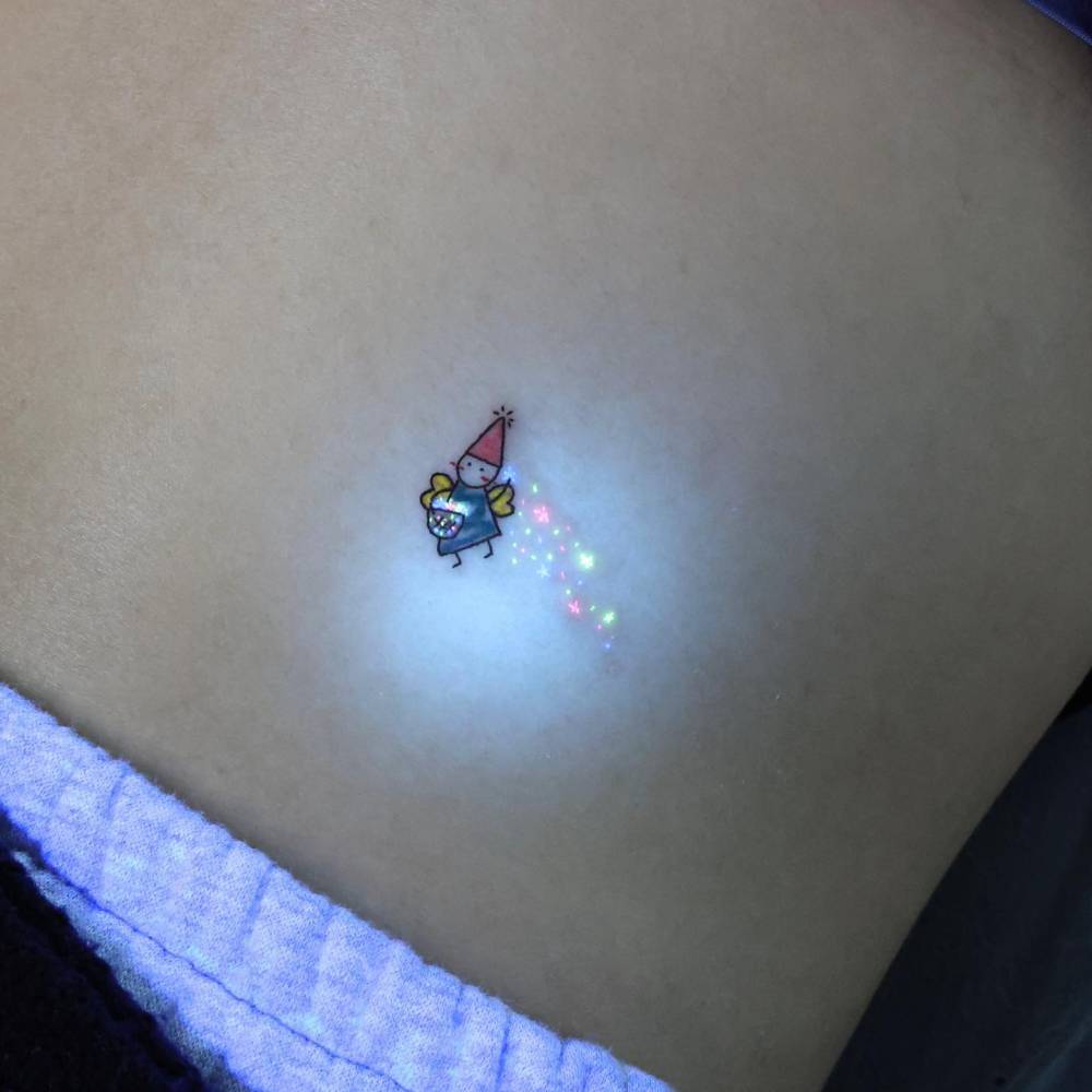 UV ink fairy tattoo in cartoon style located on the waist.
