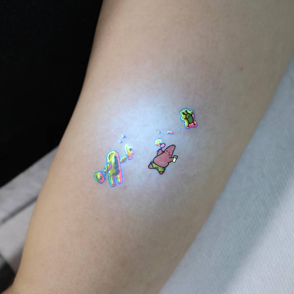 Cartoon style Patrick Star tattoo located on the upper arm.