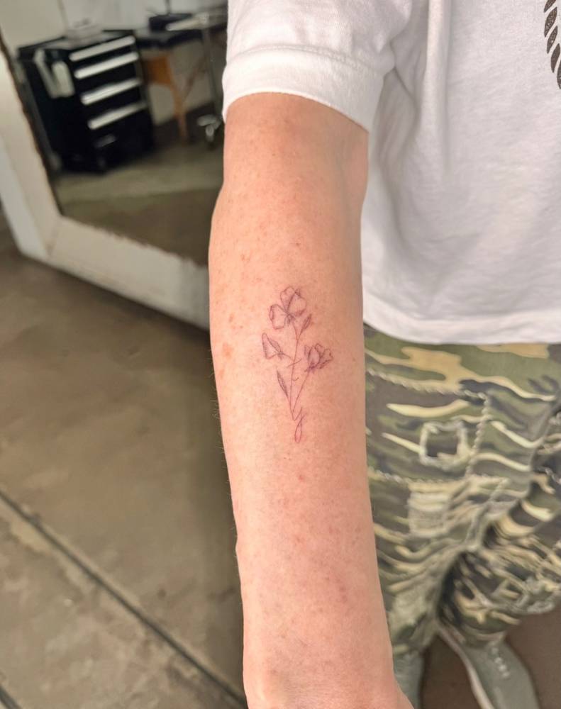 Sweet pea tattoo in fine line style located on the forearm.