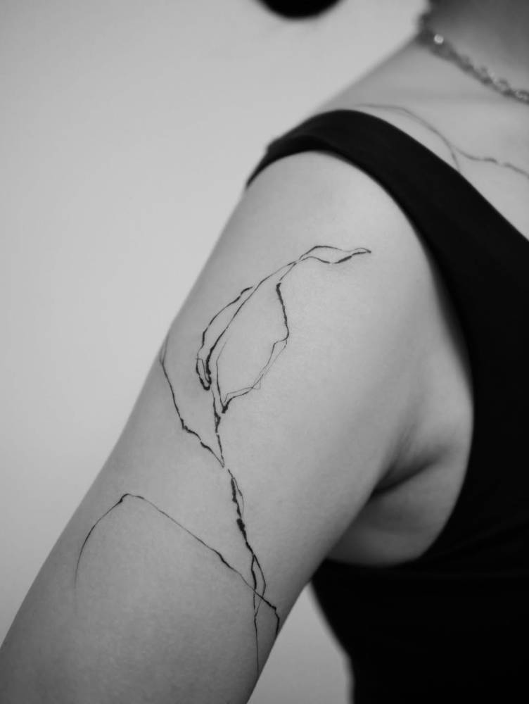 Leaf tattoo in illustrative style located on the upper arm.