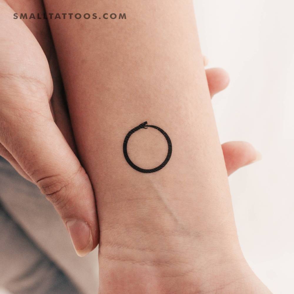 Minimalist snake ouroboros temporary tattoo located on the wrist.