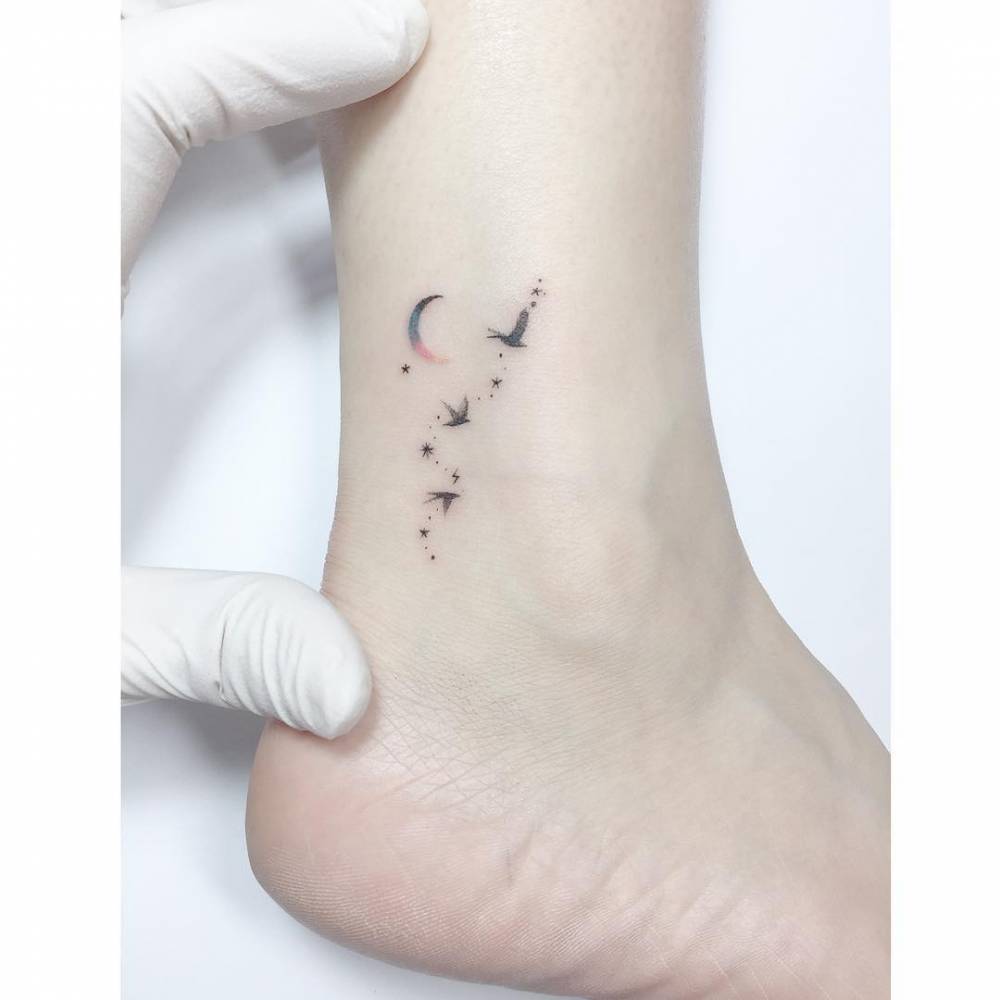 Flying birds and spectrum moon tattoo located on the ankle.