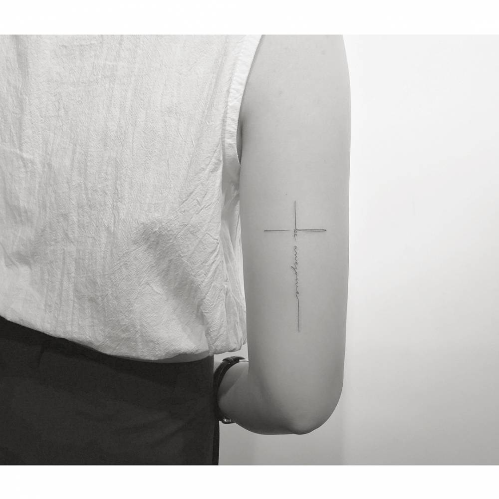 "Be awesome" lettering cross tattoo located on the wrist.