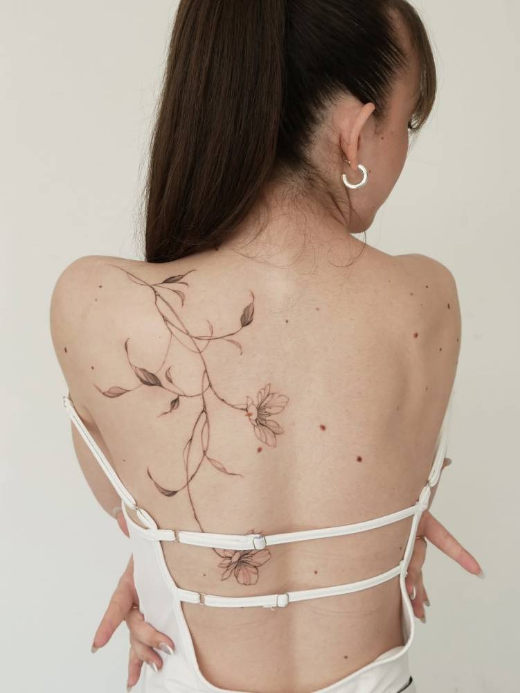 Magnolias tattoo in illustrative style placed on the back.