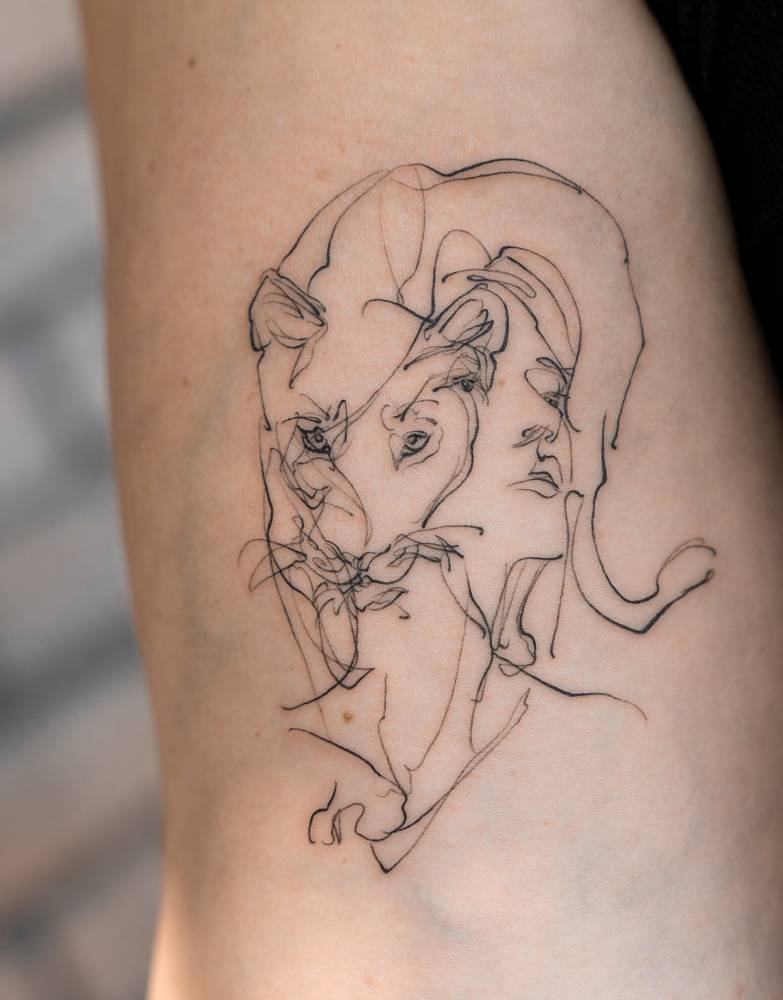 Woman and lioness portrait tattoo located on the inner arm, sketch work style.