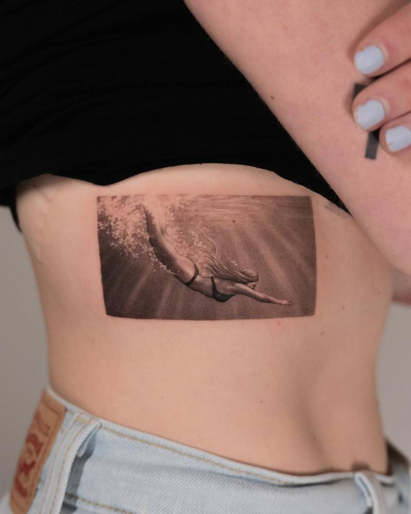 Swimmer tattoo in micro-realism located on the rib.