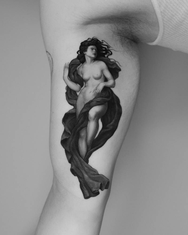 Nude woman tattoo in classical style done on the inner arm.