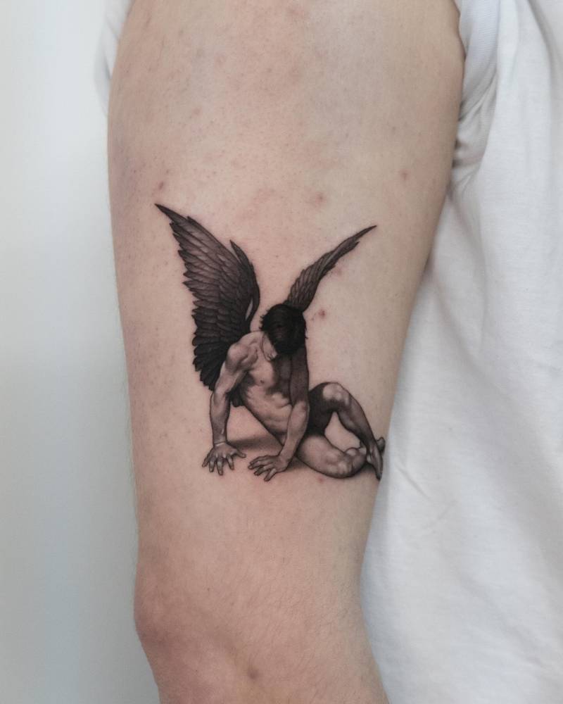 Classical style fallen angel tattoo located on the upper arm.