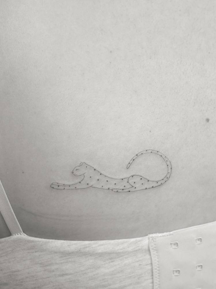 Little leopard tattoo in fine line style located on the back.