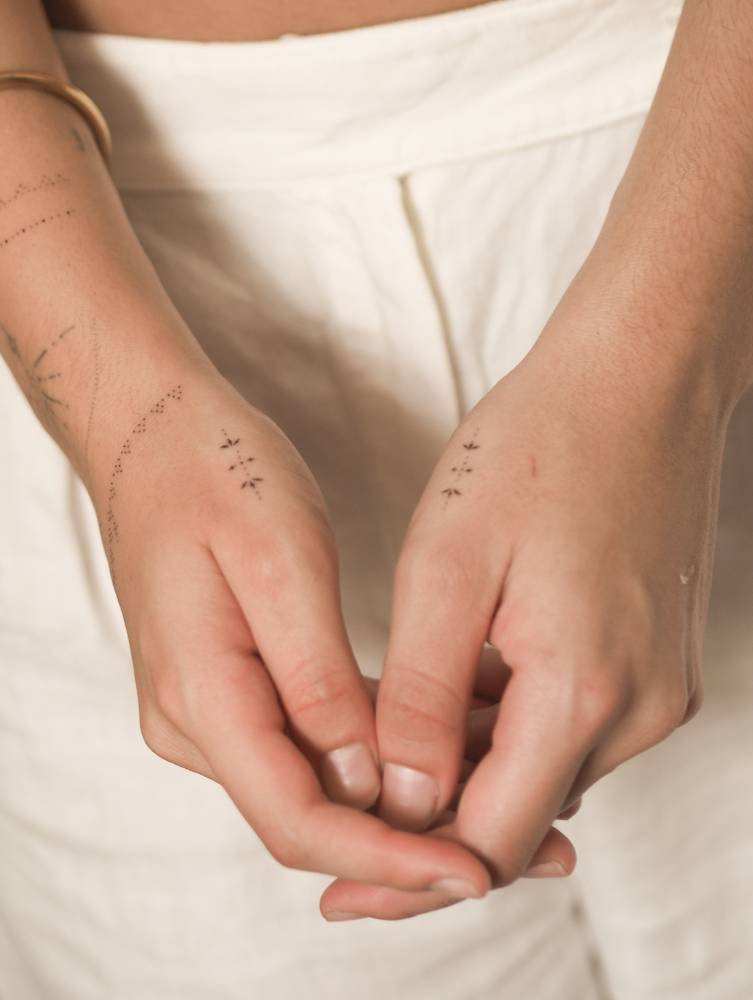 Individual matching minimalistic ornaments tattooed on the hands.