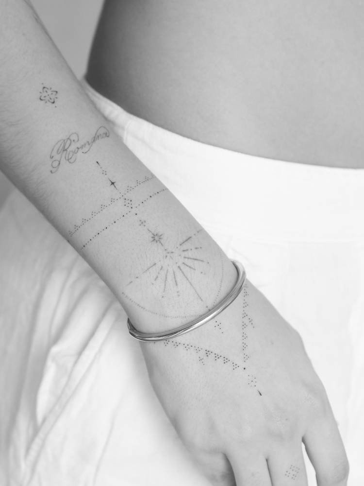 Fine line style ornamental design tattooed on the wrist.