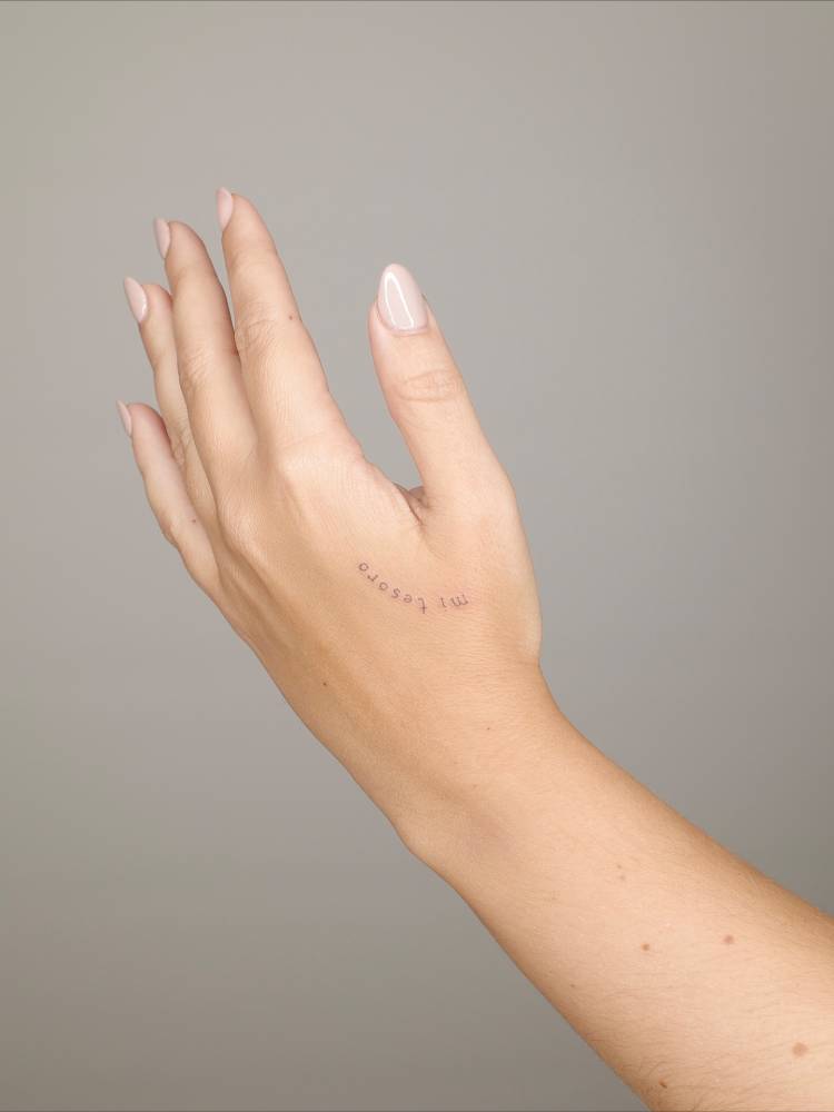 "Mi tesoro" lettering tattoo located on the hand.