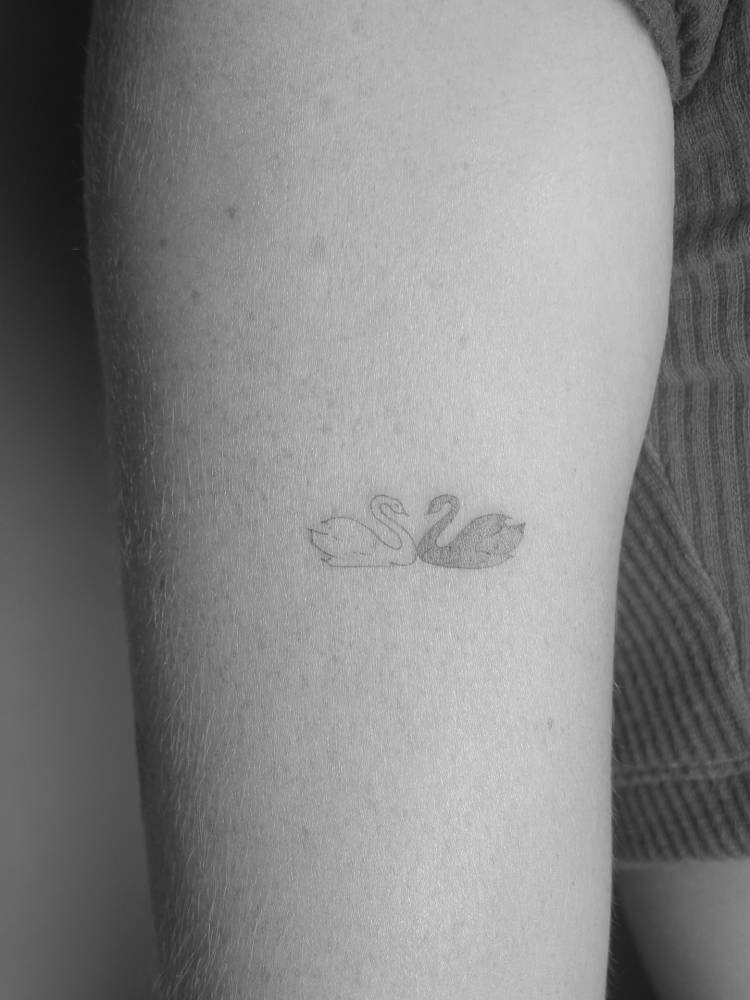 Swan couple tattoo located on the thigh, fine line style.