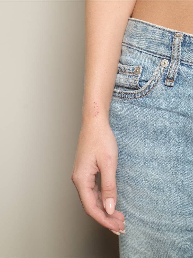 Arabic lettering tattoo located on the wrist.