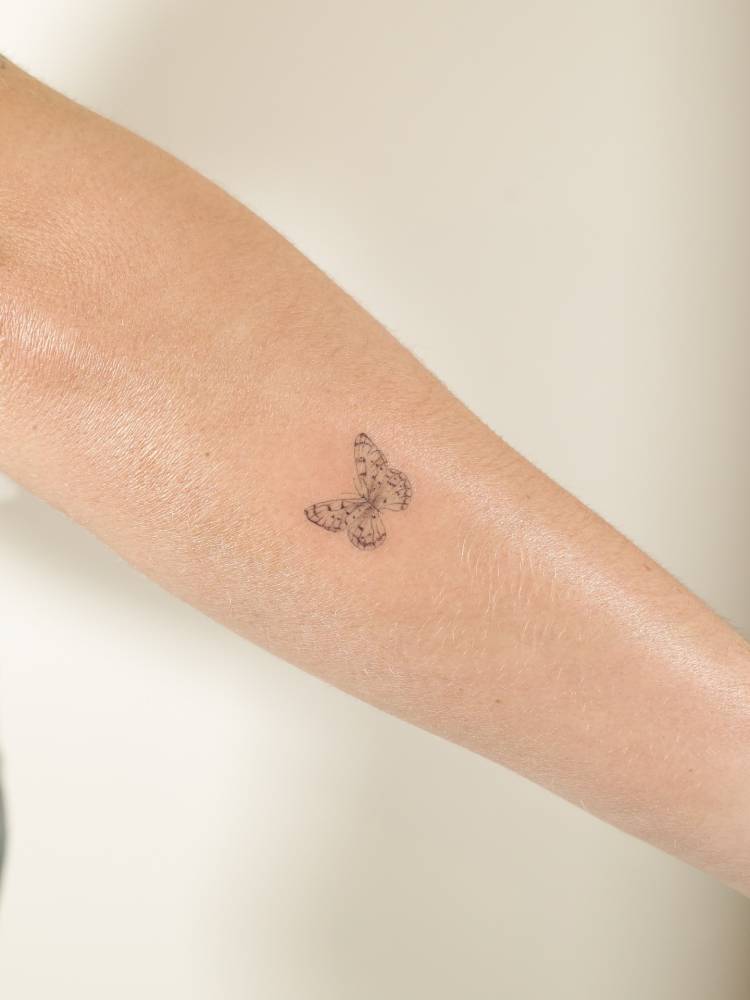 Fine line style butterfly tattoo placed on the forearm.