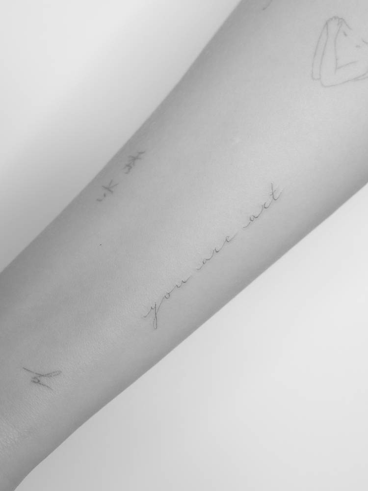 Handwritten font "you are art" lettering tattoo done on the inner forearm.