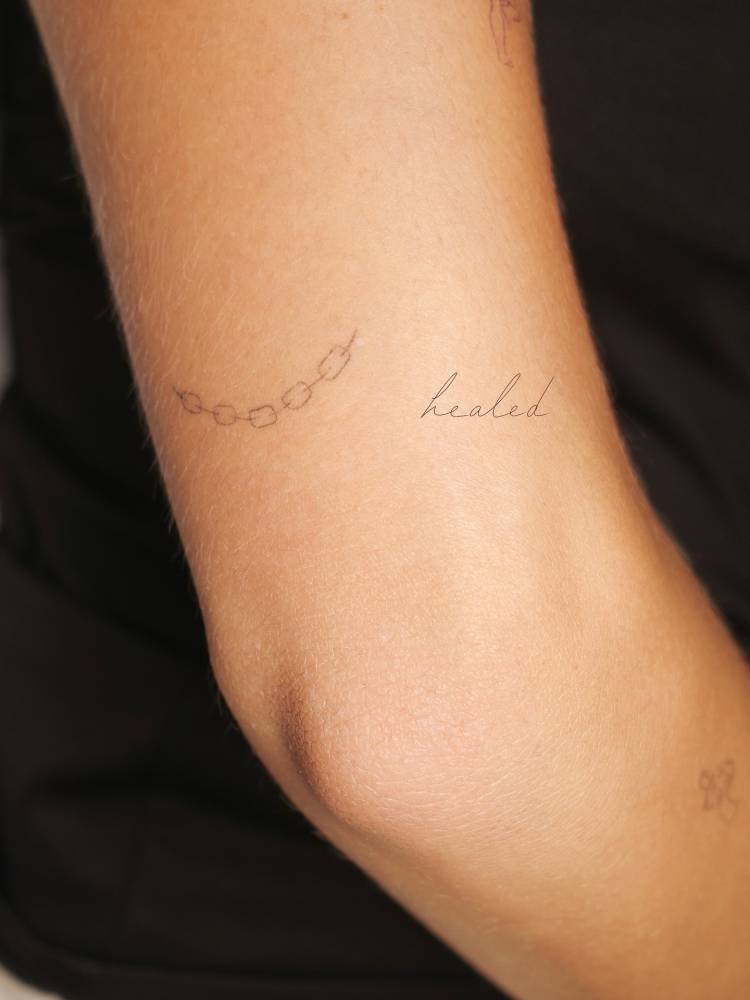 Healed chain tattoo in fine line style placed on the tricep.,
