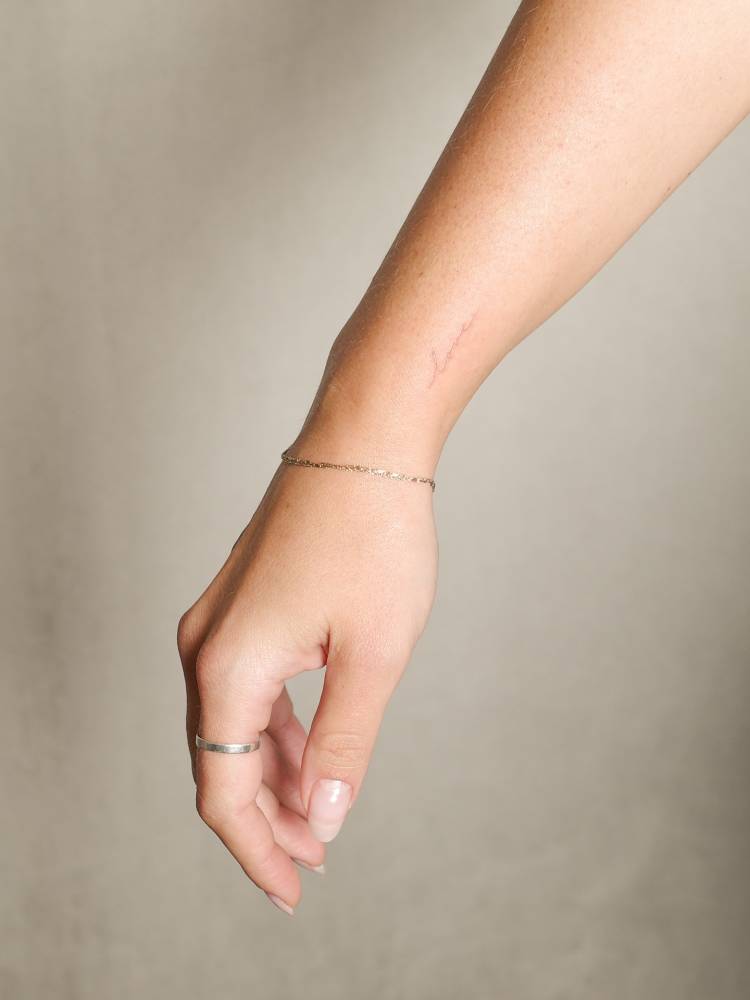 Handwritten font word "love" tattooed on the wrist.