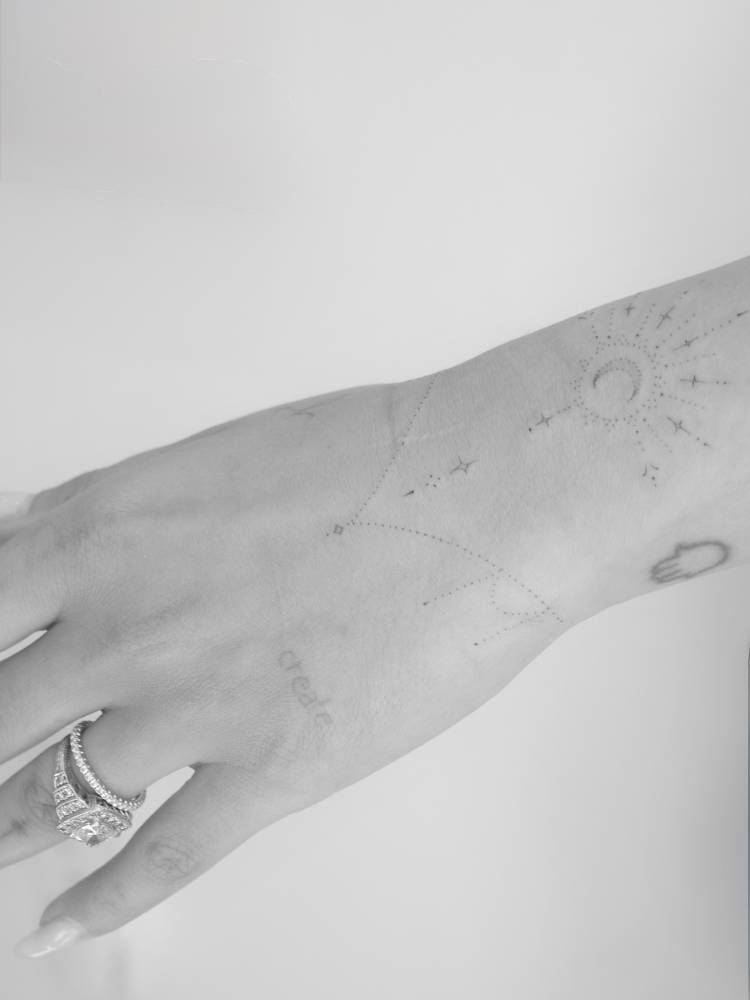 Ornamental crescent moon tattoo located on the wrist.