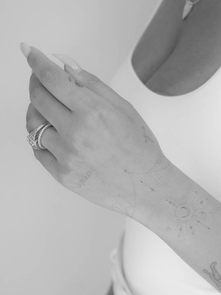 Ornamental crescent moon tattoo located on the wrist.