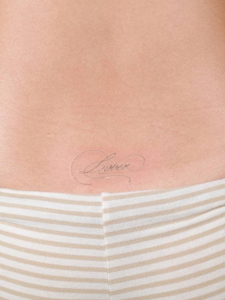Script font word "lover" tattooed on the lower back.