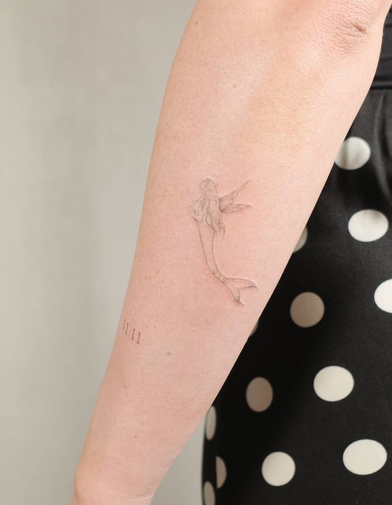Mermaid tattoo in fine line style placed on the forearm.