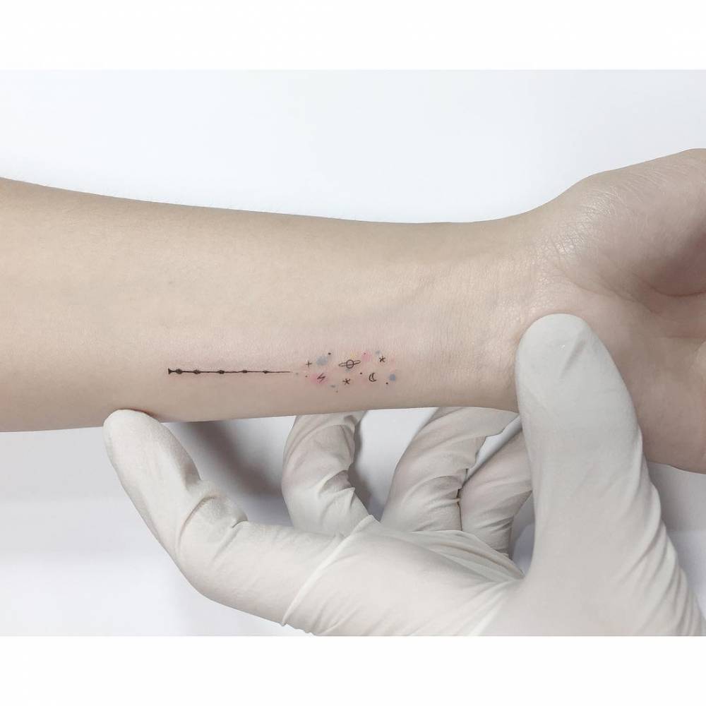 Galaxy tattoo in minimalistic style placed on the wrist.
