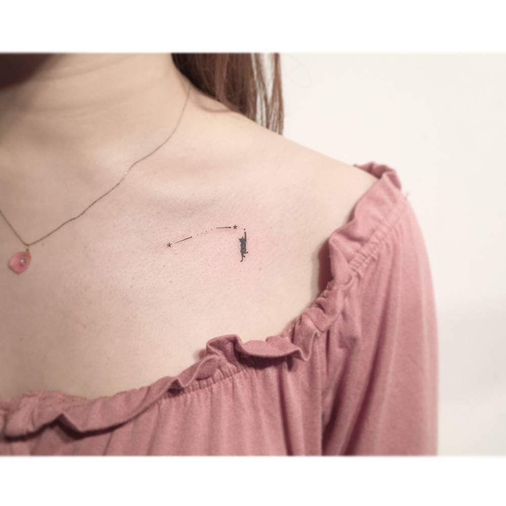 Aries constellation and black cat tattoo done on the collarbone, minimalist style.