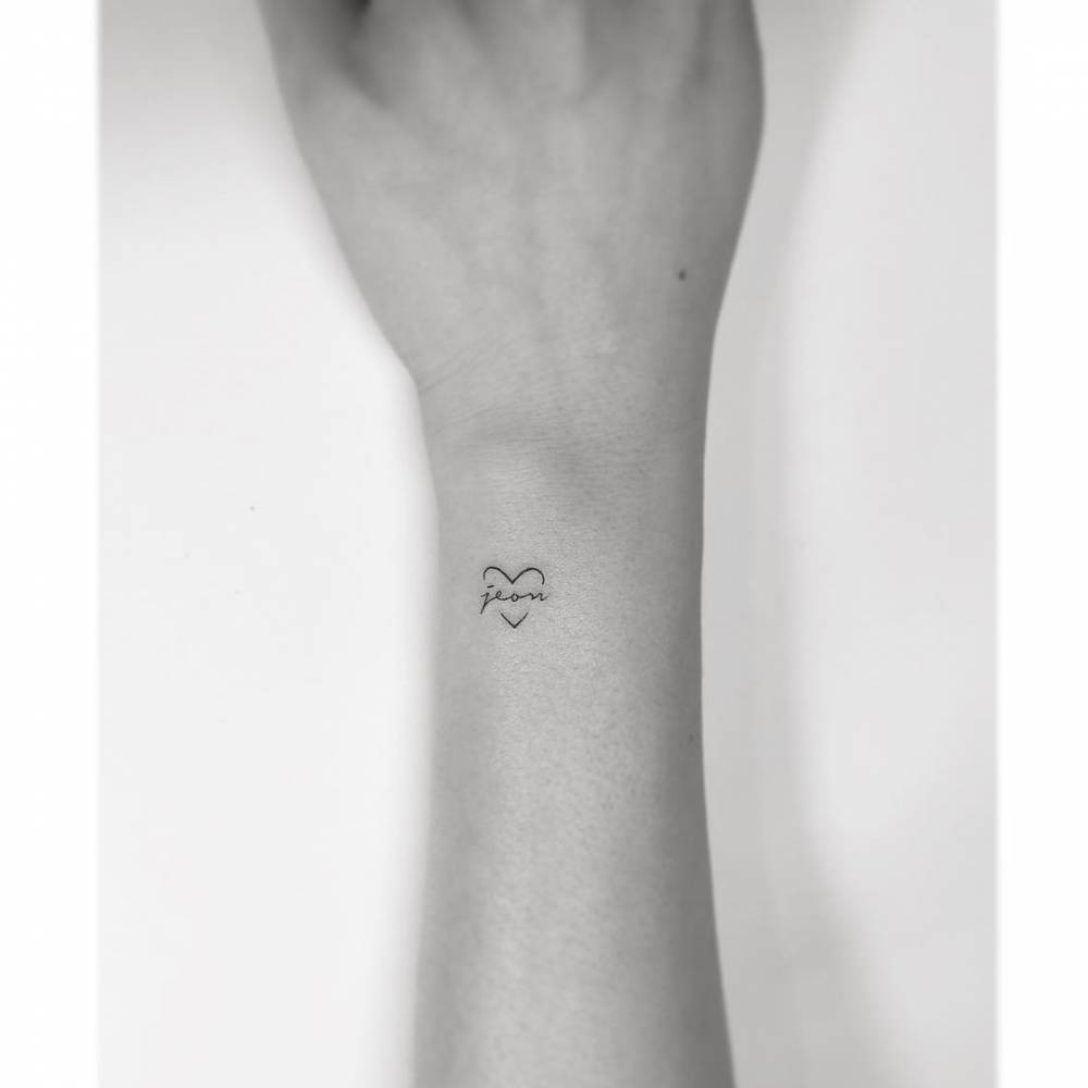 Heart and banner tattoo placed on the wrist, minimalist style.