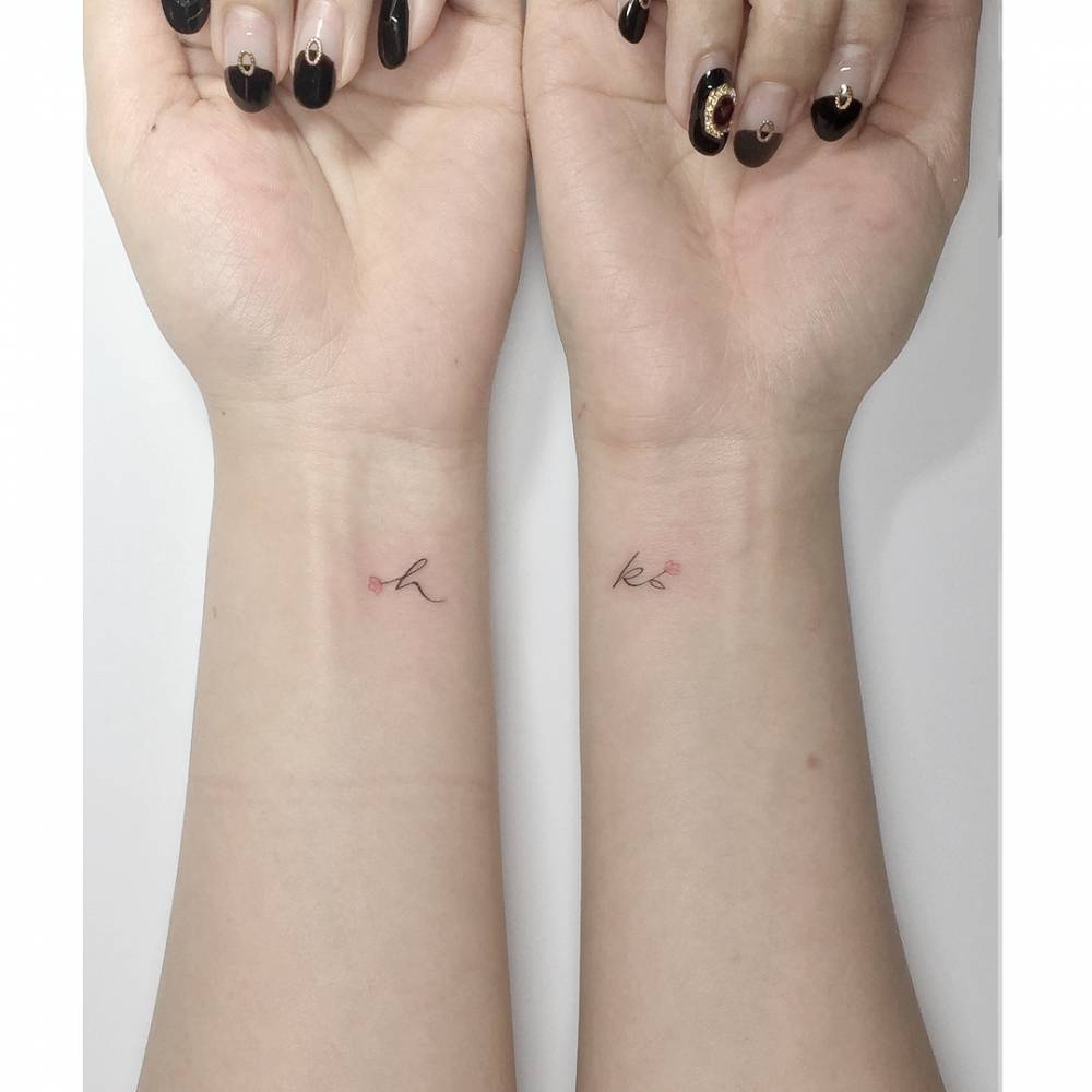 Individual matching initials and flower tattoo located on the wrists.
