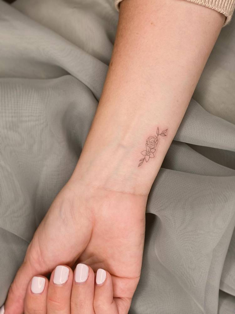 Daffodil and rose tattooed on the wrist, fine line style.