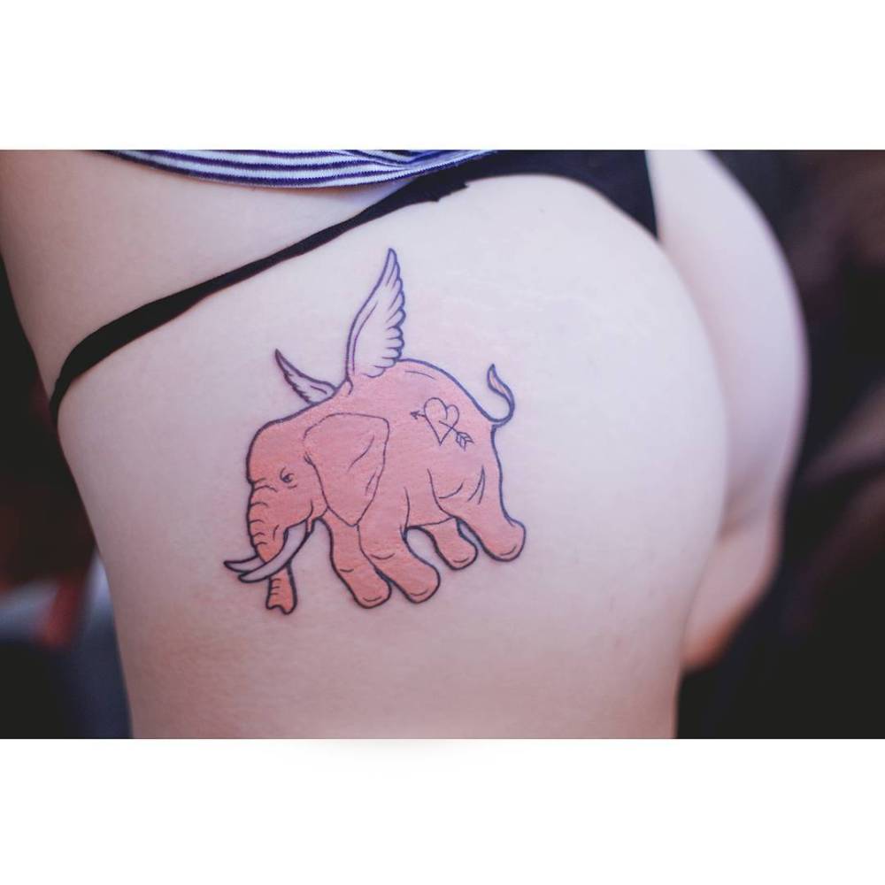 Flying elephant tattoo in cartoon style located on the butt cheek.