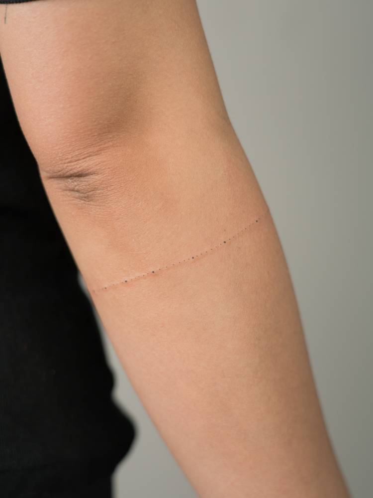 Dots armband tattoo located on the forearm, minimalistic style.