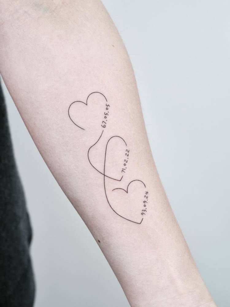Hearts and dates tattoo located on the inner forearm.