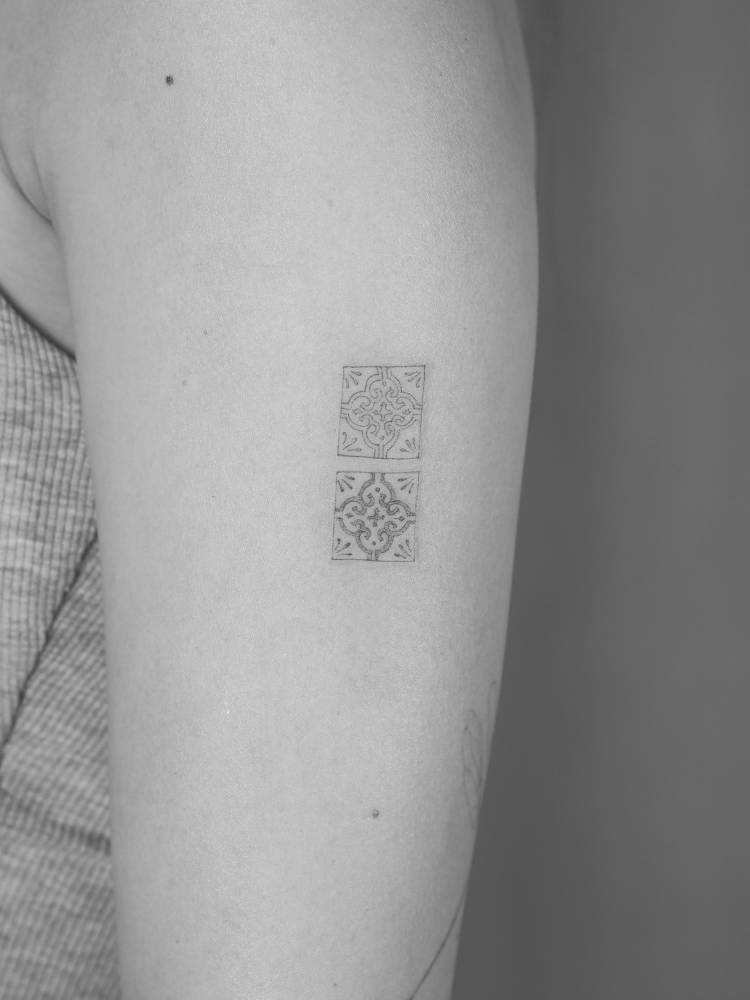 Fine line style tiles tattoo located on the upper arm.